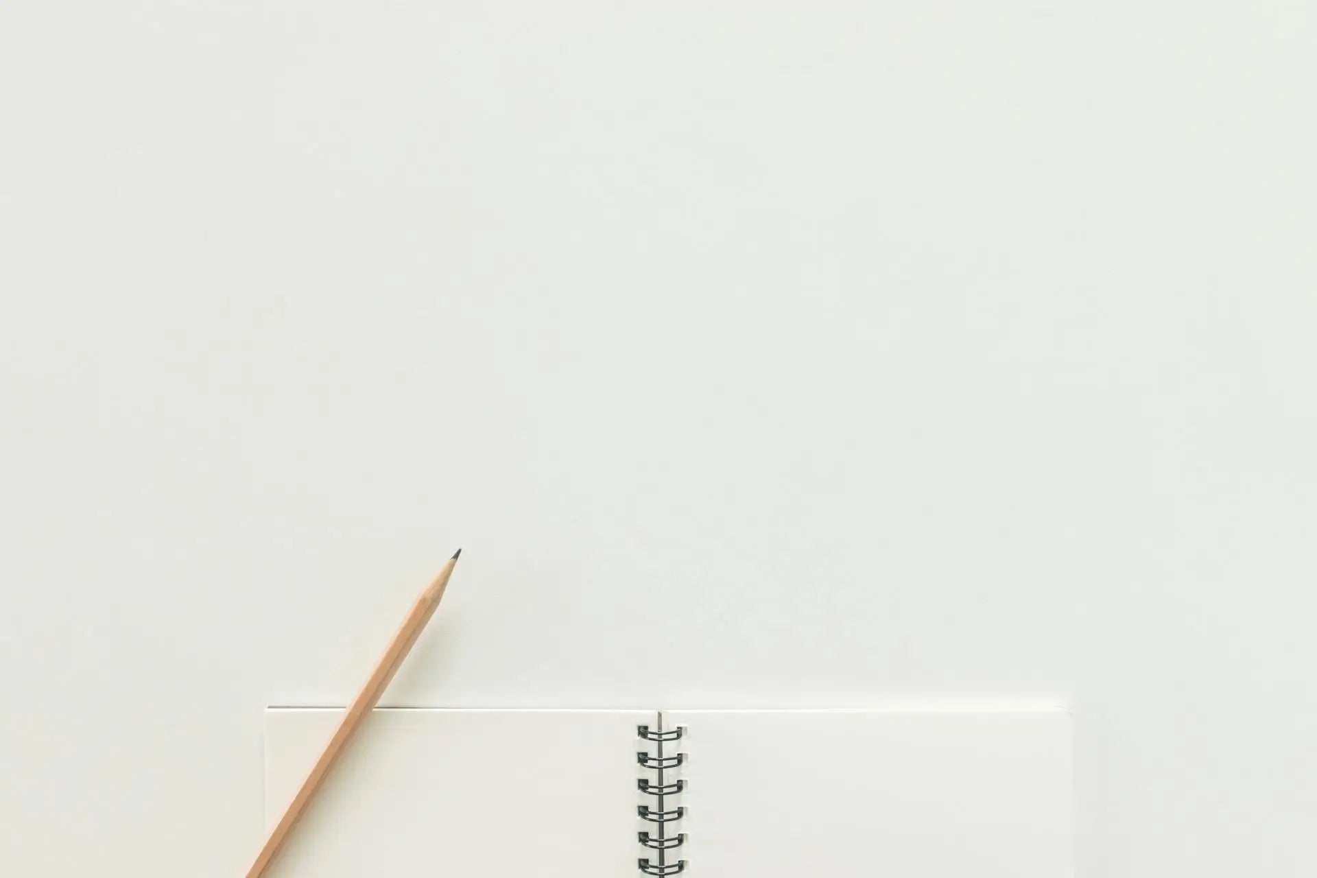 A blank spiral bound notebook pokes up from the bottom, with a pencil laying across one corner.